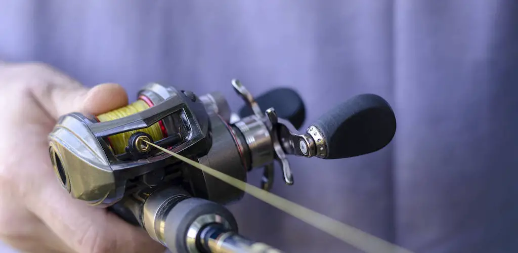 A baitcasting reel in the hand of an angler